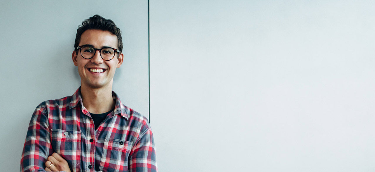 ein Mann in der Brille lehnte sich an eine Wand