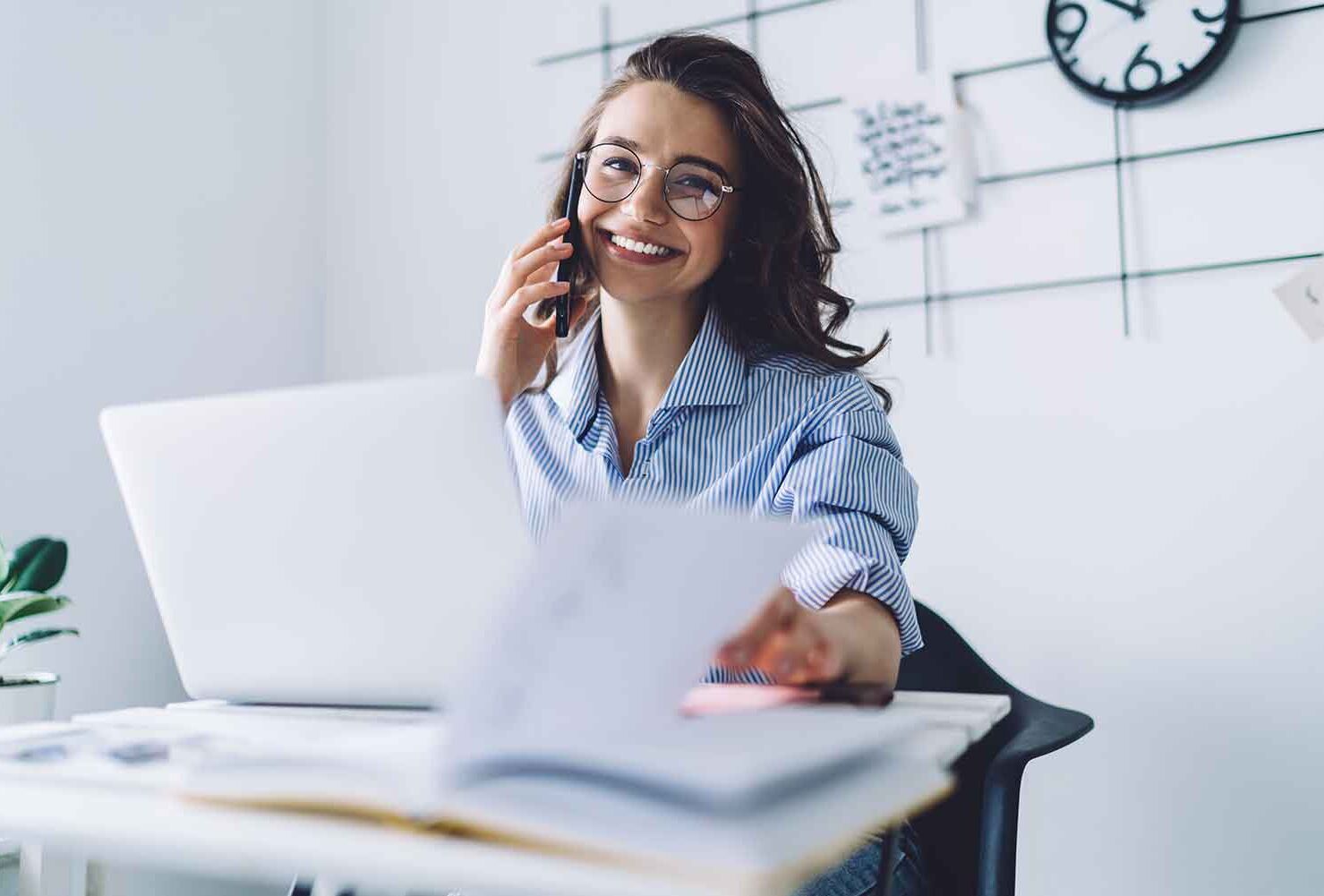 eine Frau, die an ihrem Schreibtisch sitzt und am Telefon spricht