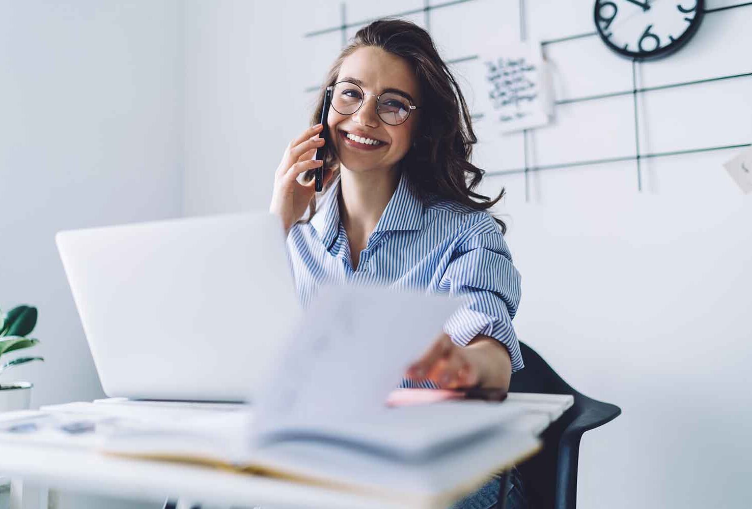 eine Frau, die an ihrem Schreibtisch sitzt und am Telefon spricht
